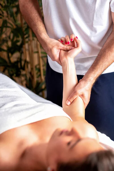 Jonge vrouw in de handen van ervaren masseur — Stockfoto