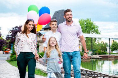 Bir lunaparkın demiryolunda duran gülümseyen aile