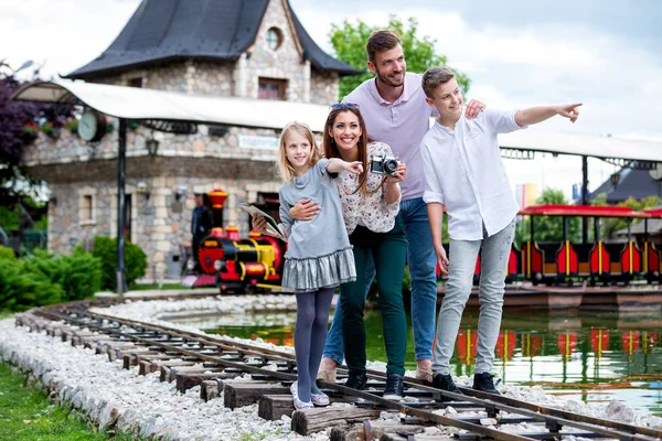 Mosolygós család áll egy vidámpark vasútjában — Stock Fotó