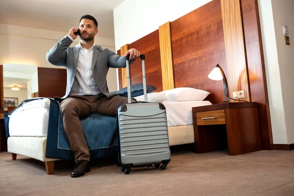 Joven hombre de negocios sentado en la cama de su habitación de hotel — Foto de Stock