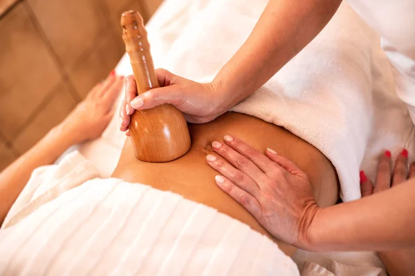 Stomach massage with hand held wooden tool