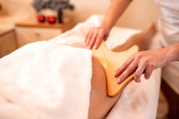 Massagista segurando uma ferramenta de massagem de madeira de mão — Fotografia de Stock