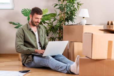 Elinde dizüstü bilgisayar olan yeni dairesinde yakışıklı adam