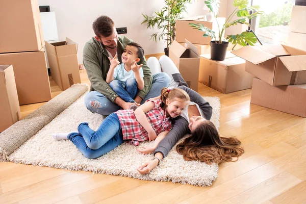 Glückliche Familie sitzt auf dem Boden ihrer neuen Wohnung — Stockfoto
