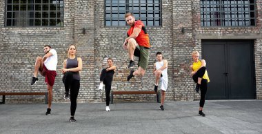 Bir grup insan ısınıyor ve egzersiz yapıyor.