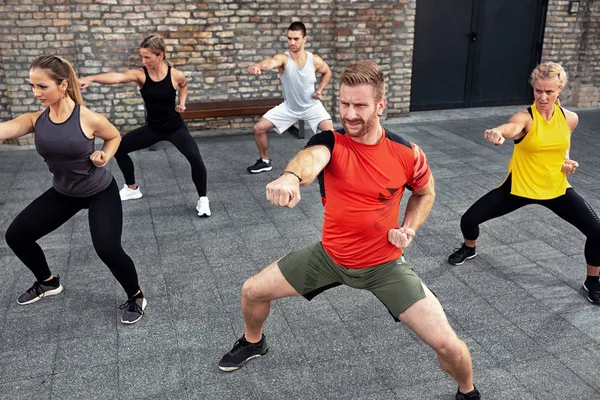 Martial artists dressed in fitness clothes practicing on the str