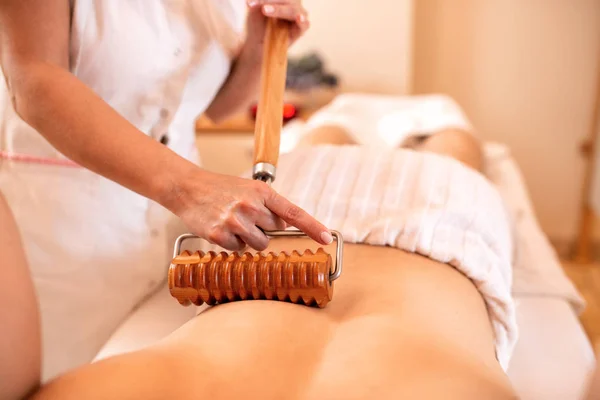 Masseuse using an extended handle roller during a massage — 스톡 사진