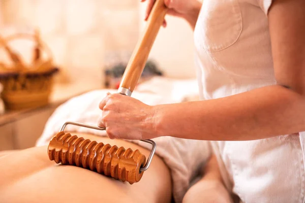 Massagem nas costas com um rolo de madeira que tem uma alça estendida — Fotografia de Stock
