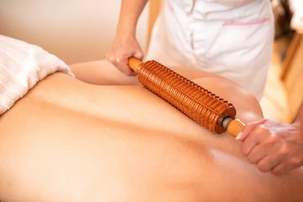 Massagista fazendo massagem nas costas com um rolo de madeira — Fotografia de Stock