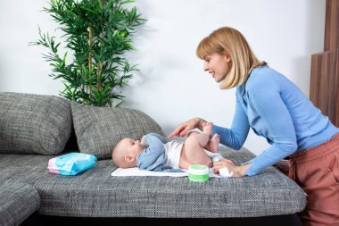 Genç anne bebeğinin altını değiştiriyor.