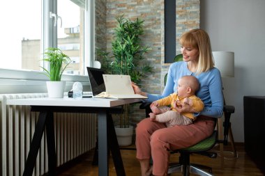 Anne ve bebek birlikte çalışıyor, evden ve ebeveynlik kavramından çalışıyor.