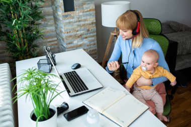 Sorumluluk sahibi bir ebeveyn çalışırken çocuğunu kucağında tutuyor.