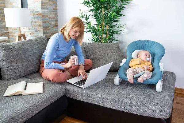 Mamãe Sentada Cama Lado Seu Bebê Jovem Laptop Segurando Café — Fotografia de Stock