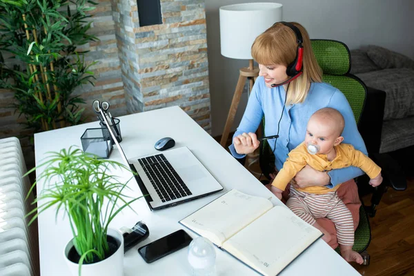 Sorumluluk sahibi bir ebeveyn çalışırken çocuğunu kucağında tutuyor.