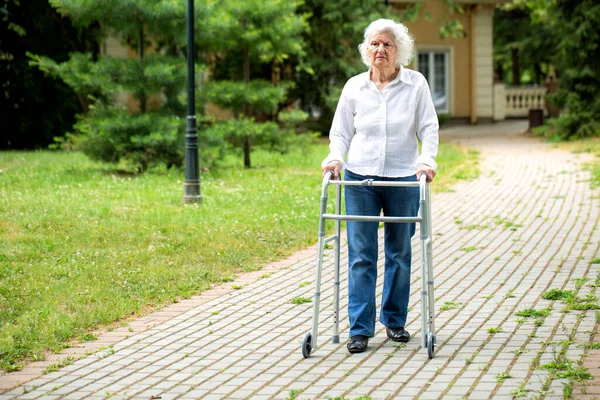 Wanita Senior Menggunakan Peralatan Berjalan Kaki Untuk Membantunya Berjalan Jalan — Stok Foto
