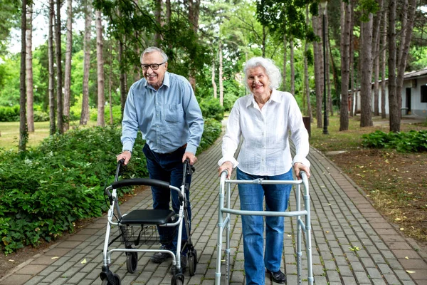 Pasangan Senior Berjalan Taman Dengan Bantuan Pembantu Berjalan Stok Gambar