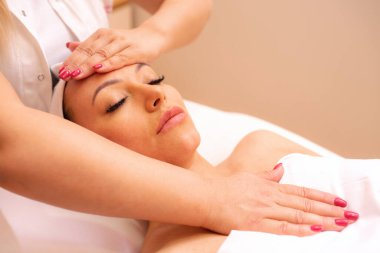 Masör müşterilerinin yüzüne masaj yapıyor, kadın güzellik salonunda.