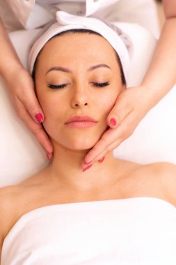 Deneyimli masöz elleri bir kadının yüzüne masaj yapıyor, sağlık ve sağlık kavramı