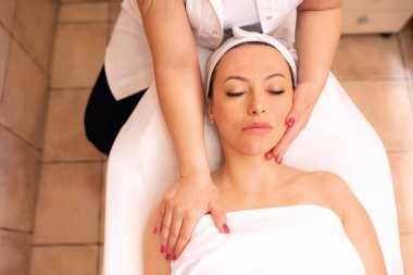 Sağlık merkezine yüz masajı yaptıran bir kadın, yüz derisi konsepti.