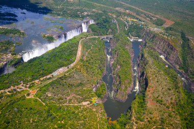 Victoria Şelalesi, Zimbabve ve Zambiya arasında, helikopterin havadan çekilmiş fotoğrafı, Afrika 'daki büyük şelalelerin çevresindeki yeşil orman. Nehrin üzerindeki Livingstone Köprüsü.
