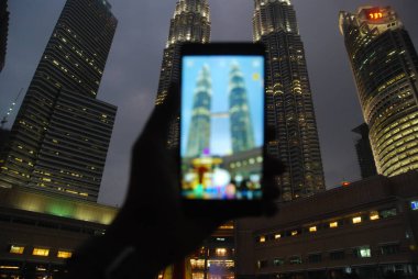 KUALA LUMPUR, MALAYSIA - February 6, 2018: A hand holding a smart phone while using camera application to capture the Petronas twin tower in Kuala Lumpur, Malaysia. 