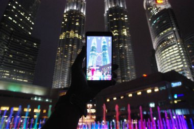 Kuala Lumpur, Malezya - 6 Şubat 2018: Kuala Lumpur, Malezya Petronas İkiz kule yakalamak için Kamera uygulamasını kullanırken bir akıllı telefon tutan bir el. 