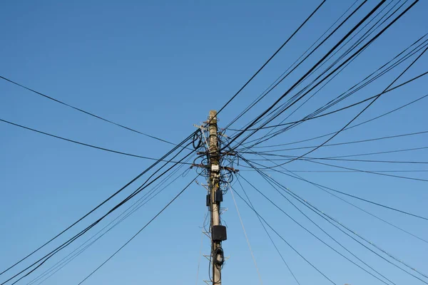 青い空の下で木製の棒に接続されている電気通信線の大きな混乱の詳細 — ストック写真