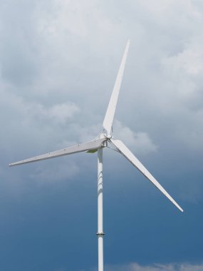 Jeneratör, güç ünitesi (Wpu), enerji dönüştürücü. Gökyüzünde çelikten yapılmış beyaz rüzgar türbinleri yavaşça dönüyor.