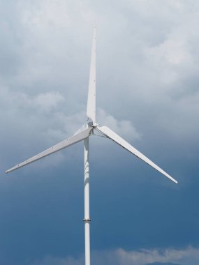 Jeneratör, güç ünitesi (Wpu), enerji dönüştürücü. Gökyüzünde çelikten yapılmış beyaz rüzgar türbinleri yavaşça dönüyor.