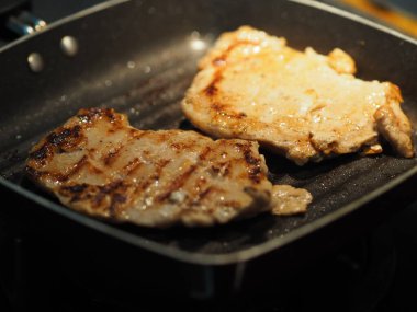 Biberli domuz bifteği ve siyah tavada kızartılmış domuz sosisi yemek için pişirilmiş.