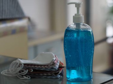 Masada toz ve El dezenfektanını korumak için kumaştan yapılmış hasta yüz maskesi önleme masası, temiz plastik şişede jelatin ve temiz plastik şişeyle karıştırılmış çamaşır yıkama suyu, mikropların bulaşıcı Corona virüsünü, covid-19 'u korumak için kirli çamaşır yıkama.