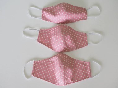 Pembe kumaş grubundaki üç boyutlu beyaz nokta, toz ve mikropları korumak için hastalıklı bir maske takıyor. Öğleden sonra 2.5, Coronavirus covid-19.