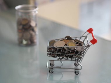 Süpermarketteki mini model arabalardan ve arka plandaki temiz plastik kutularda bir sürü bozuk para var.