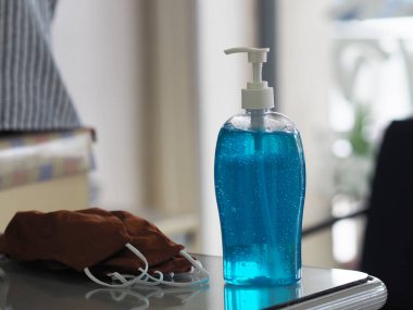 Kumaş yüz maskesi ve el dezenfektanı masada, jel alkollü karışım temiz plastik şişede jelatin ve pompa ile temiz çamaşır yıkama, mikropların bulaşıcı corona virüsünü korumasını önlemek için kirli çamaşır yıkama, covid-19