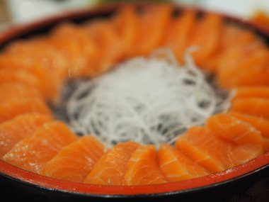 Tahta tepsi şeklinde Japon yemeği serpiştirilmiş taze somon balığı dilimi.