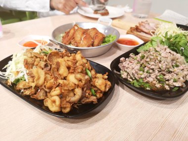 Kızarmış domuz bağırsağı üstü çıtır sarımsak, biber ve lahana, ince dilimlenmiş siyah tabak, domuz salatası, kızarmış tavuk kanadı, Tayland yemeği mis kokulu çıtır çıtır