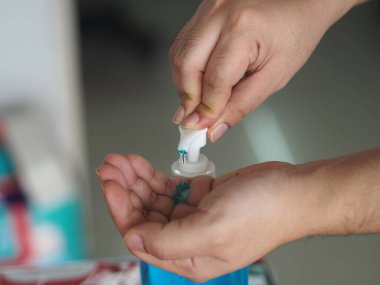 Eline jel damlatan kadın jöle tutan el dezenfektanı, temiz plastik şişede jelatinle karışık jöle tutan pompalı çamaşır yıkayan kadın bulaşıcı korona virüsünü, covid-19 virüsünü korumak için kirli çamaşır yıkayan kadın.