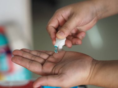 Eline jel damlatan kadın jöle tutan el dezenfektanı, temiz plastik şişede jelatinle karışık jöle tutan pompalı çamaşır yıkayan kadın bulaşıcı korona virüsünü, covid-19 virüsünü korumak için kirli çamaşır yıkayan kadın.