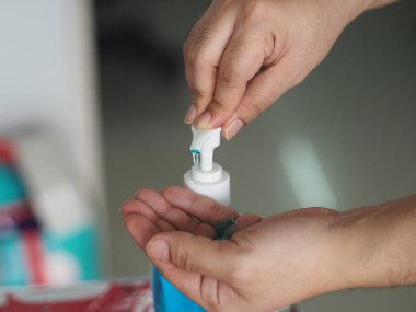 Eline jel damlatan kadın jöle tutan el dezenfektanı, temiz plastik şişede jelatinle karışık jöle tutan pompalı çamaşır yıkayan kadın bulaşıcı korona virüsünü, covid-19 virüsünü korumak için kirli çamaşır yıkayan kadın.