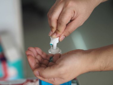 Eline jel damlatan kadın jöle tutan el dezenfektanı, temiz plastik şişede jelatinle karışık jöle tutan pompalı çamaşır yıkayan kadın bulaşıcı korona virüsünü, covid-19 virüsünü korumak için kirli çamaşır yıkayan kadın.