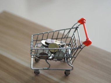 Tahta masadaki mini model market arabalarına para koyuyor.