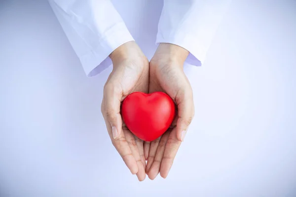 Женщина-врач руки держа красное сердце на белом фоне пожертвовать — стоковое фото