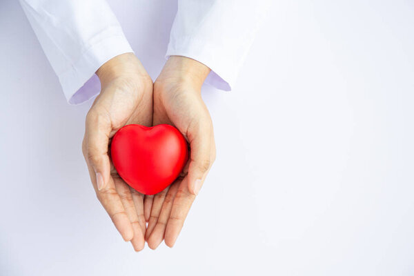 Woman doctor hands holding red heart on white background donate 