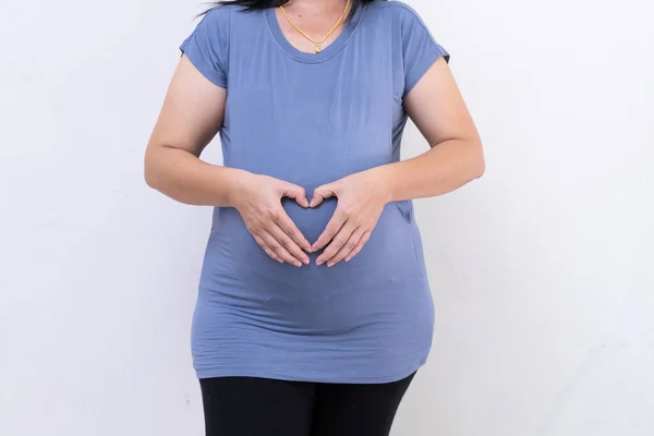 Pregnant woman in blue dress holds belly on a white background. — Stock Photo, Image