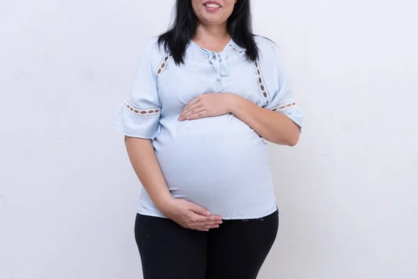 身穿蓝色衣服的孕妇在白色背景下抱着肚子. — 图库照片