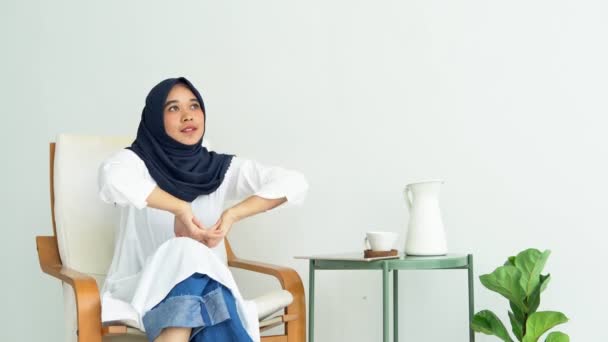 若いイスラム教徒の女性学生は タブレット携帯電話のスマートフォンでアジアの民族の喜びのインターネットバンキングヒジャーブの女の子イスラム教のための起業家の仕事の概念であることを書いて創造的なフリーランスのジャーナリスト座っている — ストック動画