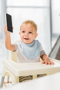 şirin yürümeye başlayan çocuk holding smartphone el gülümseyen ve bebek koltuğunda oturmak