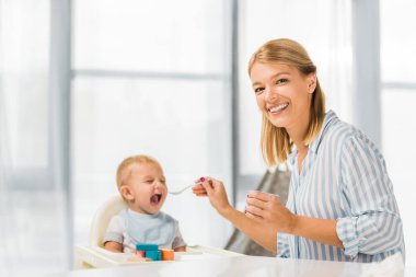 mutlu anne oğlu ile bebek maması sandalyesi besleme 