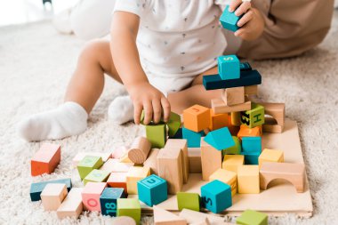 cropped view of adorable toddler playing with colorful cubes clipart