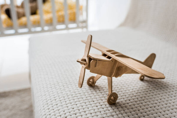 ретро деревянный игрушечный самолет на диване в детской комнате
